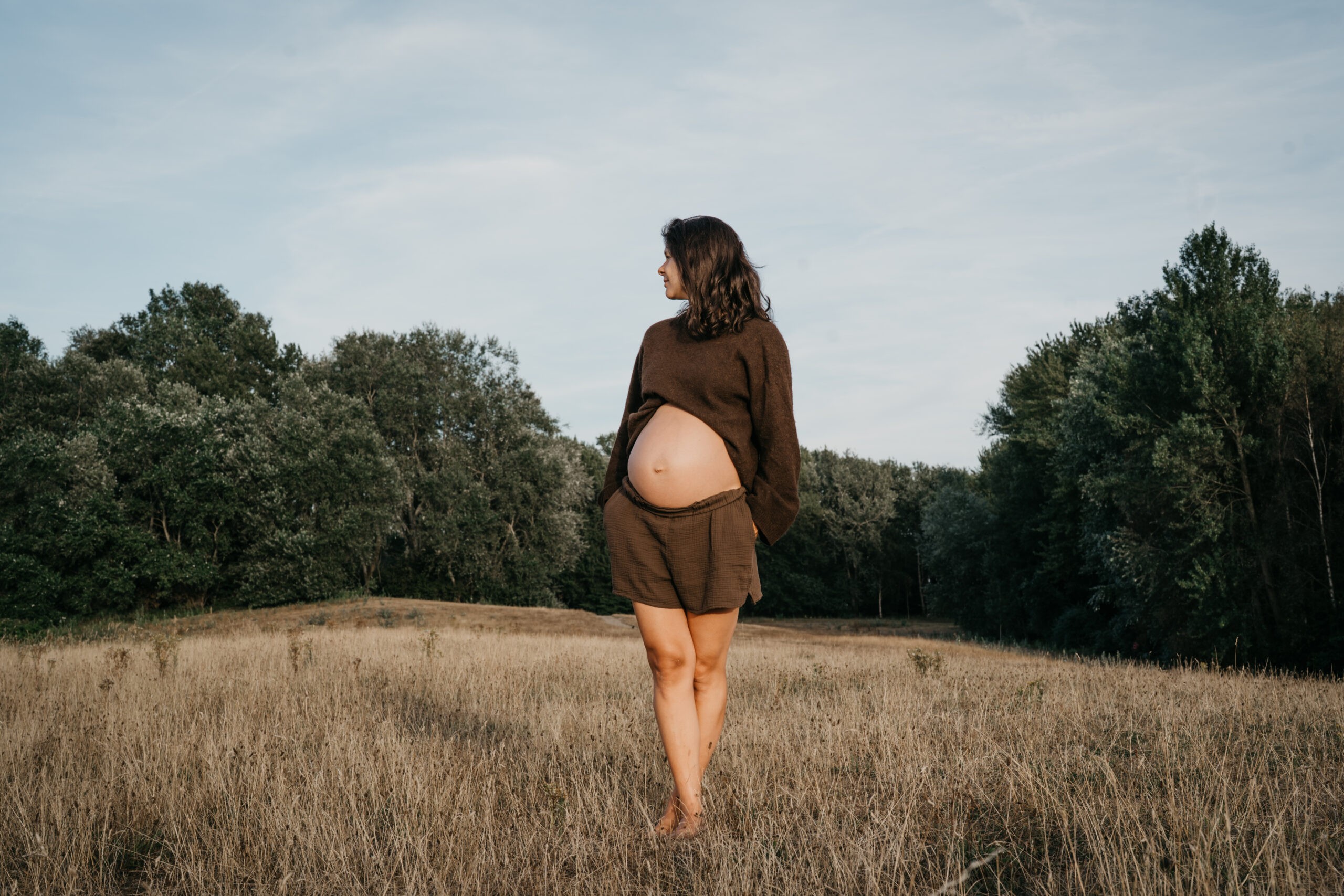 Zwangere vrouw poseert op een heuvel in het bos bij Amsterdam
